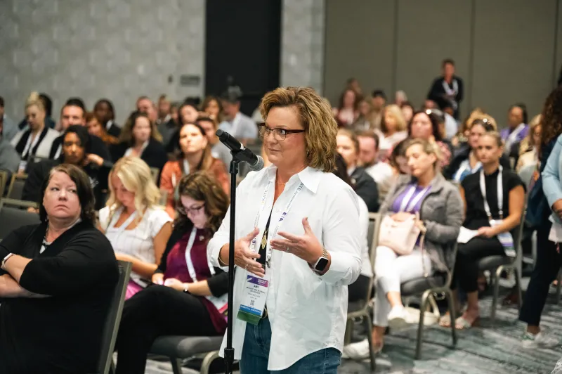 Woman speaking in a room full of people. 