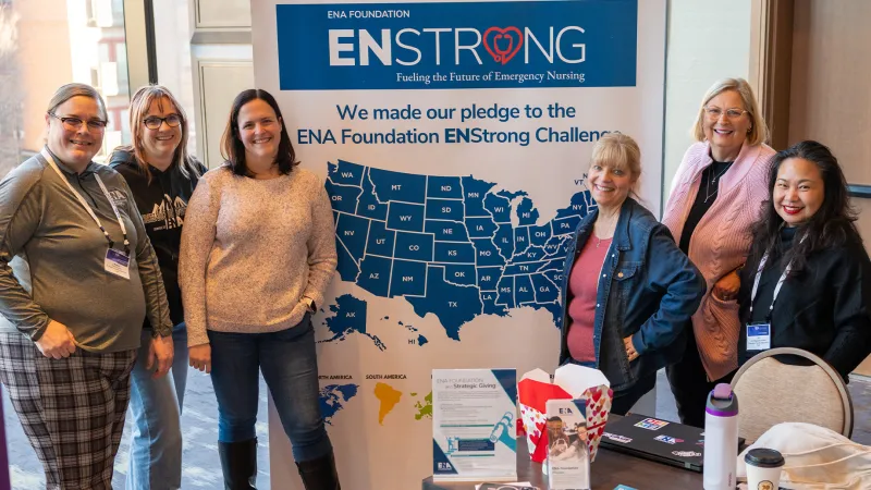Group of smiling ENA Staff at the ENA Leadership Conference posing in front of a ENStrong Pull Up Banner